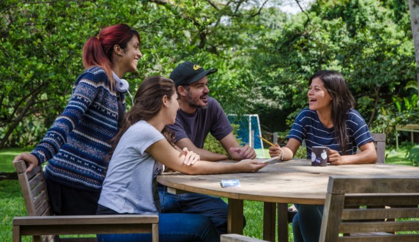 A group of people sitting around a table in a park.