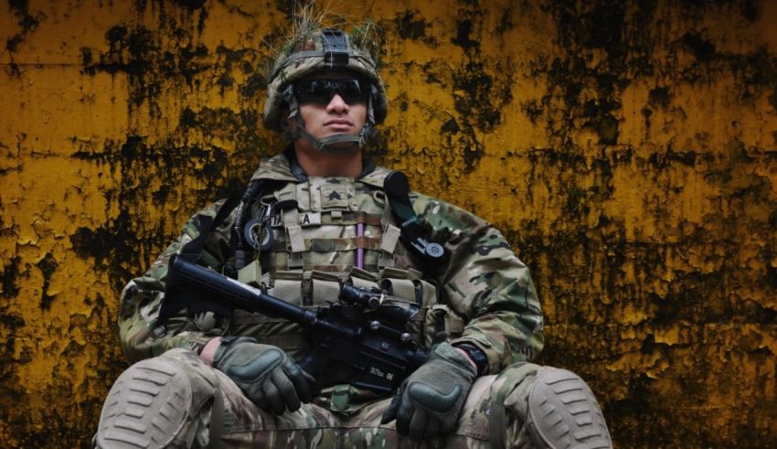 A soldier is sitting on the ground with a rifle.