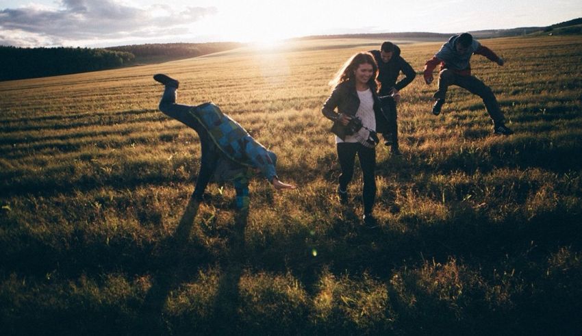 A group of people running through a field at sunset.