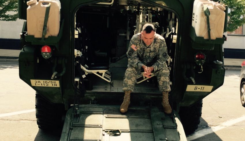 A soldier sits in the back of an armored vehicle.