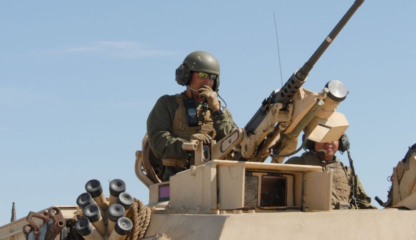 A soldier is sitting on top of an armored vehicle.