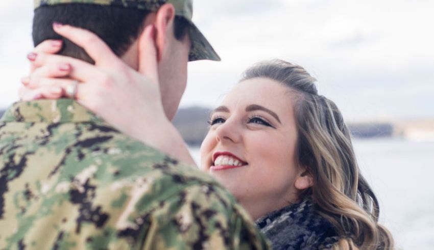A man in a military uniform is hugging a woman.