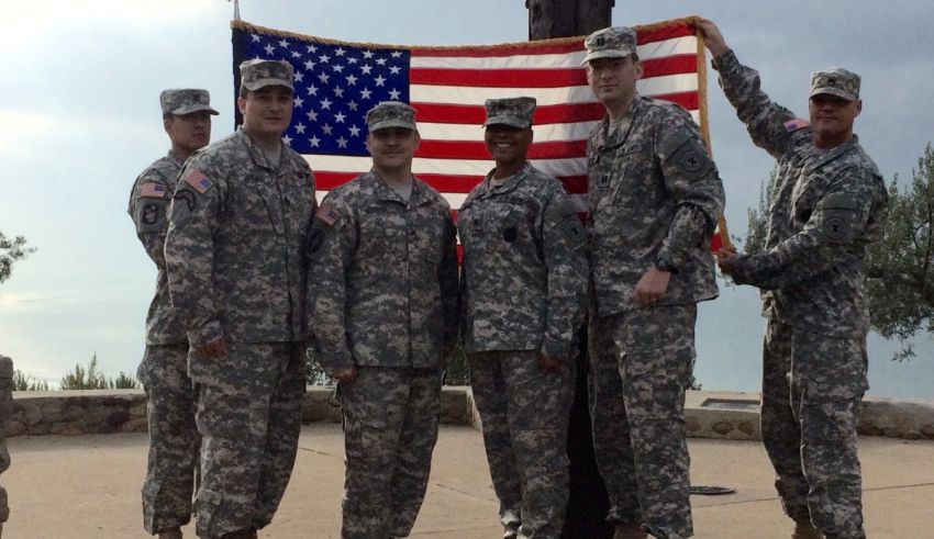 A group of soldiers posing with an american flag.