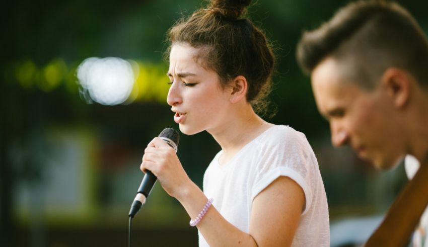A woman singing into a microphone while a man plays an acoustic guitar.