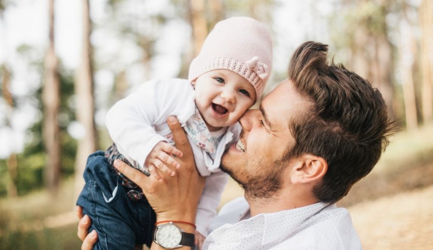 A man is holding a baby in his arms in the woods.