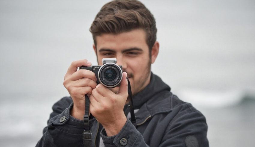 A man with a camera taking a picture of the ocean.