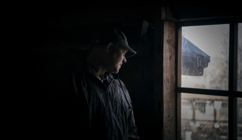 A man looking out a window in the dark.