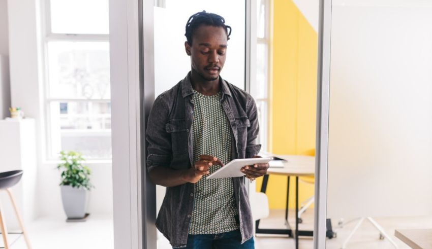 A black man using a tablet in an office.