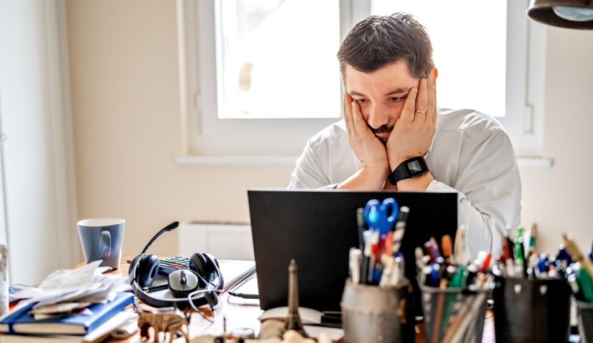 A man is sitting at a desk with a laptop in front of him.