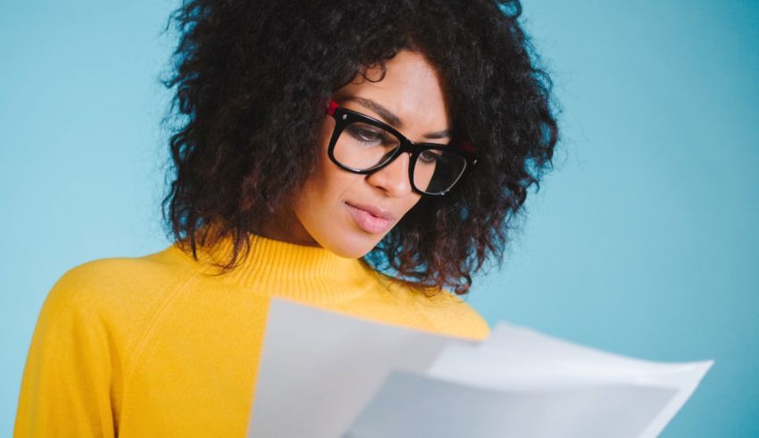 Young african american woman in glasses reading a document.