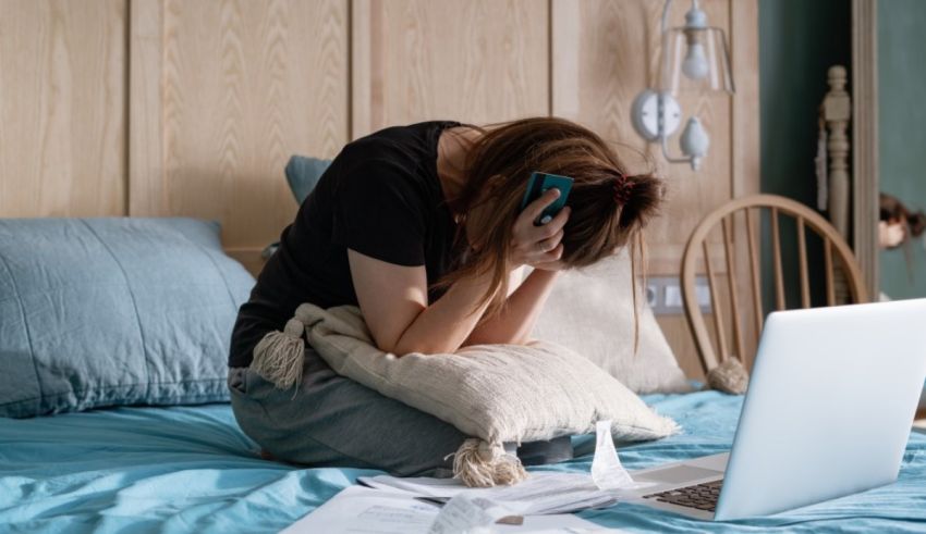 A woman sitting on a bed with a laptop on her lap.