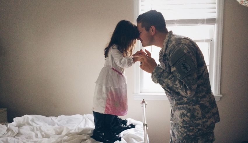 A soldier kissing a little girl on the bed.