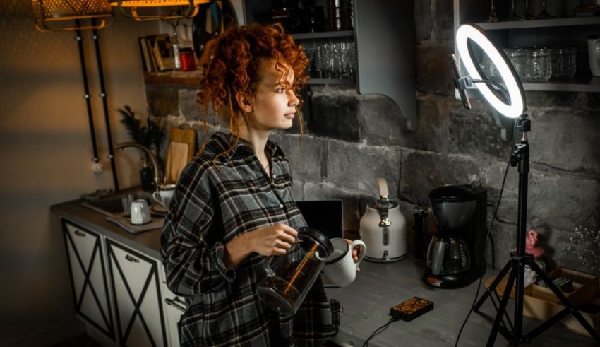 A woman is standing in front of a ring light in a kitchen.