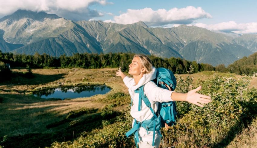 A woman hiking in the mountains with her arms outstretched.