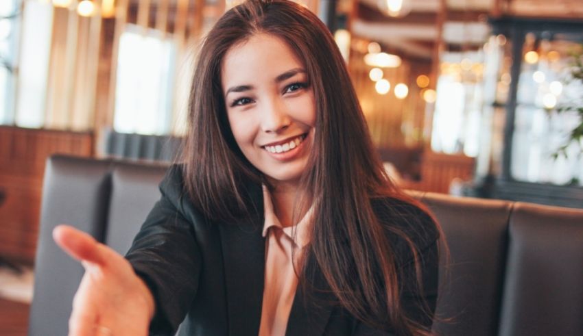 A business woman is sitting at a table with her hand outstretched.