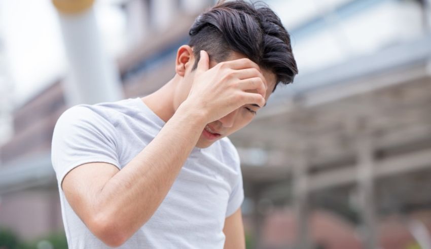A young man is holding his head in pain.