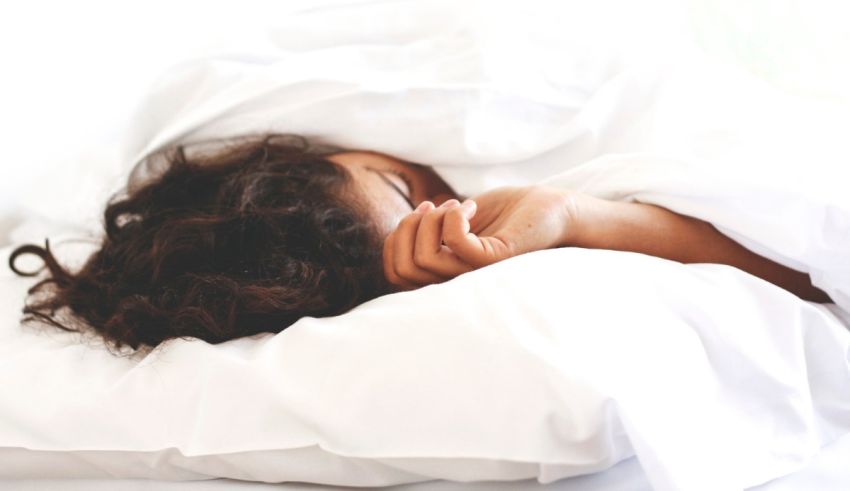 A woman is sleeping in a bed with white sheets.