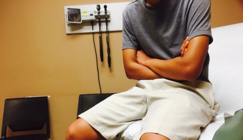 A young man sitting on a hospital bed with his arms crossed.