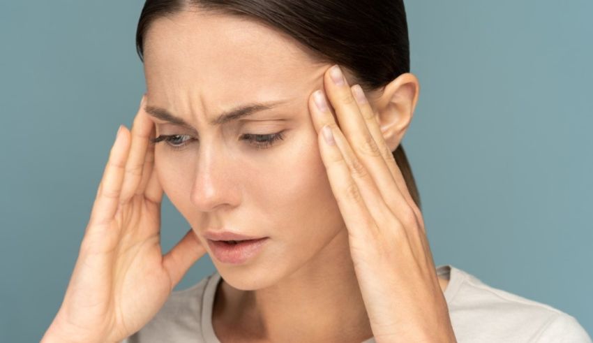 A woman with a headache holding her hands on her head.
