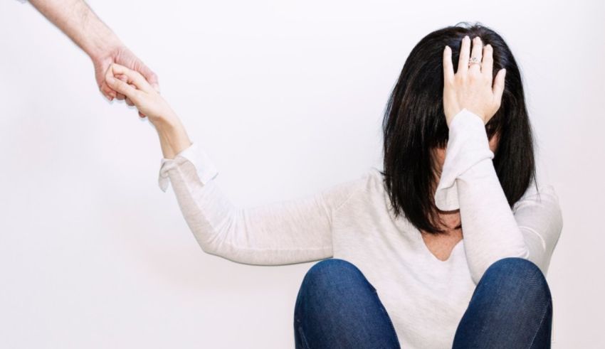 A woman is sitting on the floor with her hands on her head.