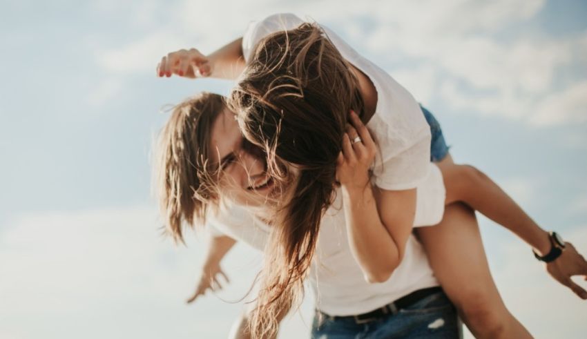 A man is piggybacking a woman on the beach.