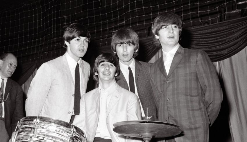 The beatles posing for a photo with a drum.