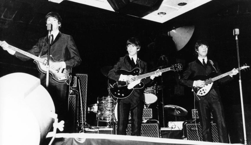 The beatles on stage with guitars.