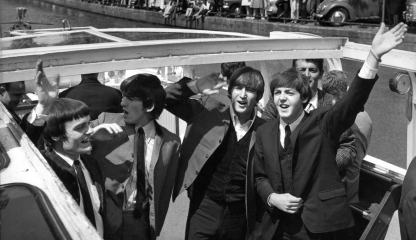 The beatles on a boat waving to the crowd.