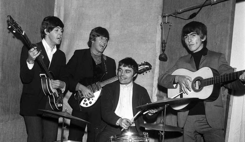 A black and white photo of the beatles in a recording studio.