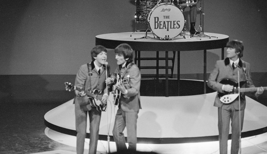 The beatles on stage with guitars and drums.