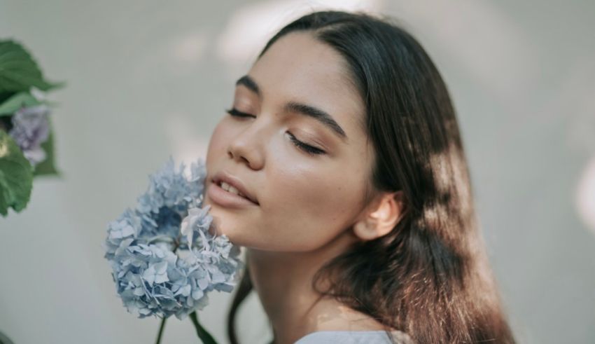 A woman holding a blue flower with her eyes closed.