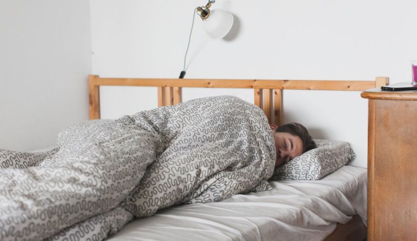 A man sleeping on a bed with a blanket.