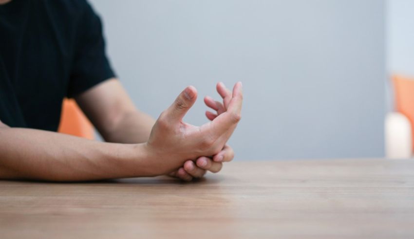 A man is sitting at a table with his hands on his knees.