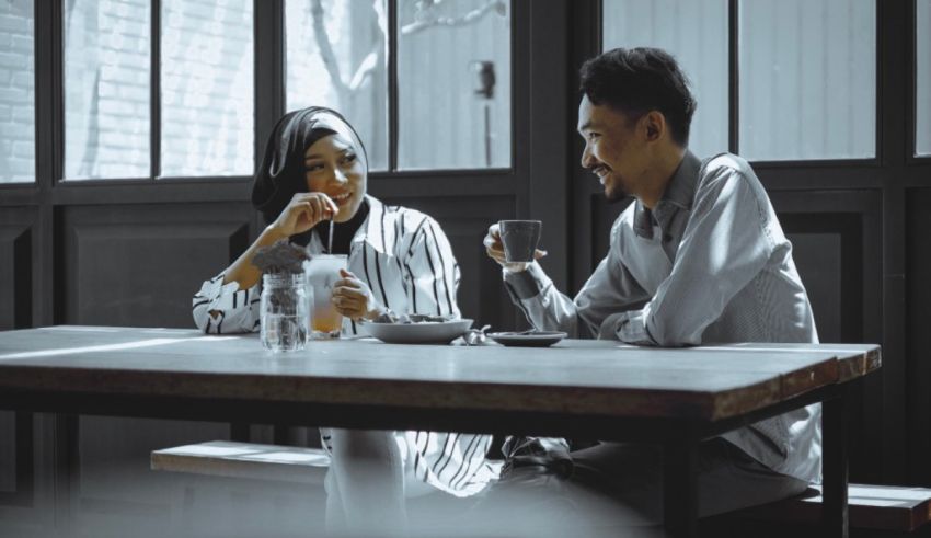A man and woman sitting at a table drinking coffee.