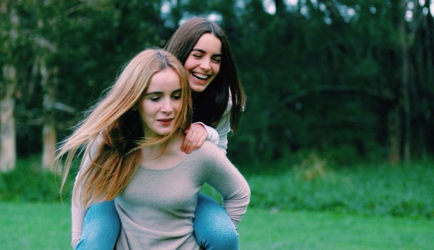 Two girls are playing in a grassy field.