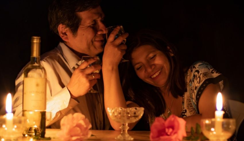 A man and woman sitting at a table with candles.