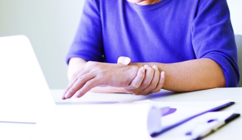 A man sitting at a desk with a wrist band on his wrist.