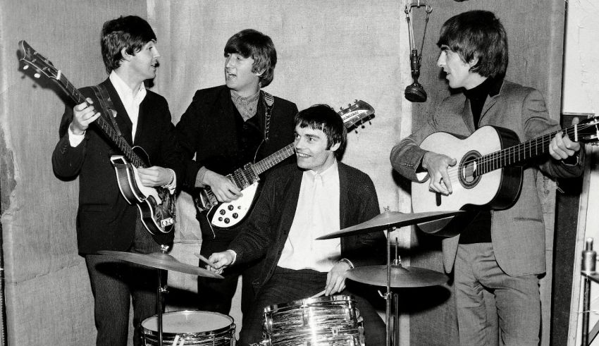 A black and white photo of the beatles in a recording studio.