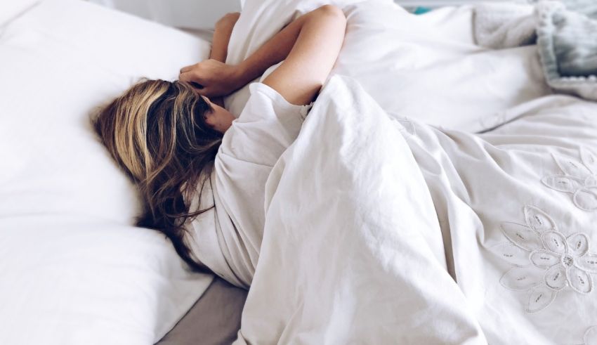 A woman laying in bed with a white blanket.