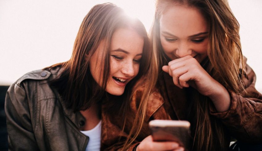 Two young women looking at their cell phones.