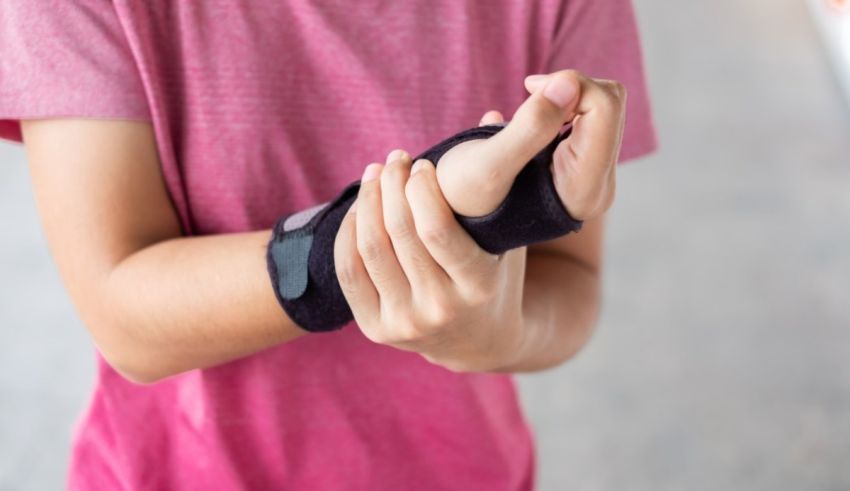 A boy is holding his wrist with a bandage on it.
