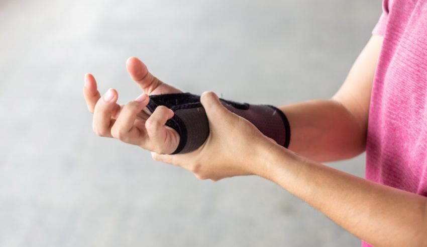 A woman is holding her wrist with a bandage on it.