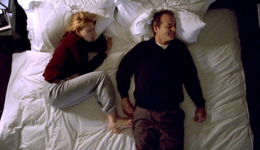 A man and woman laying on a white bed.