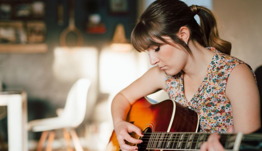 A woman playing an acoustic guitar in a living room.