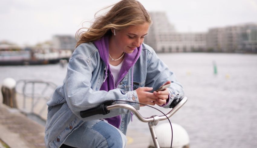 A young woman on a bicycle using her cell phone.
