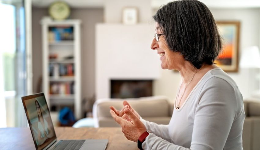 A woman is sitting at a table with a laptop in front of her.