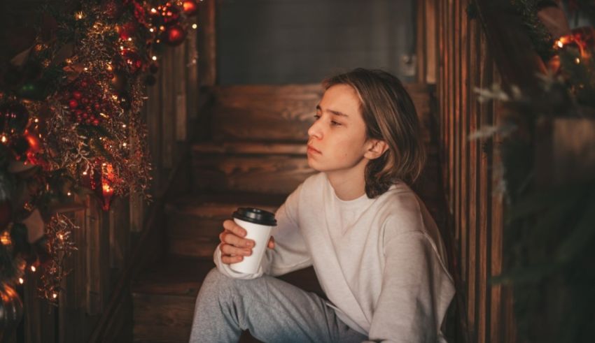 A woman sitting on the stairs holding a coffee cup.