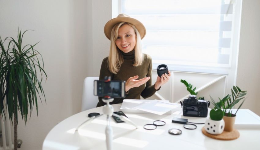 A woman sitting at a table with a camera and other equipment.