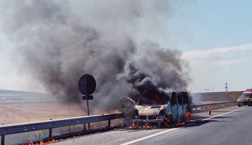 A car is burning on the side of the road.