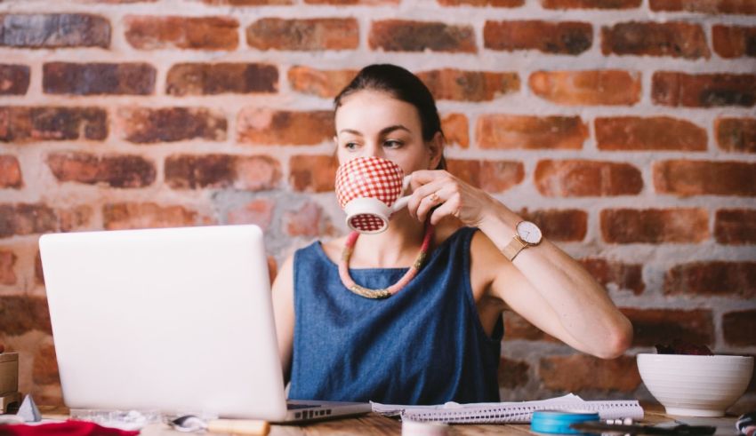 A woman sitting at a desk with a laptop and a cup of coffee.